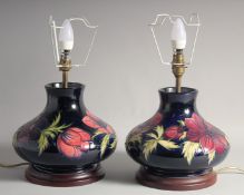 A VERY GOOD PAIR OF MOORCROFT CIRCULAR BULBOUS LAMPS on a blue background. 8.5ins high, 9ins