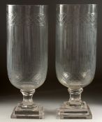 A PAIR OF CUT GLASS STORM LANTERNS on square stepped bases. 16ins high.