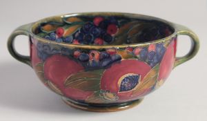 WILLIAM MOORCROFT POMEGRANATE DESIGN CIRCULAR TWO HANDLED BOWL on a green ground. Signed: W.