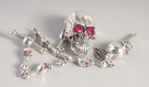 A SILVER PLATED SKULL SNUFF BOX on a chair.