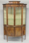 A GOOD EDWARDIAN MAHOGANY STANDING DISPLAY CABINET of serpentine outline, with a pair of glazed
