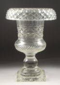 A CUT GLASS URN SHAPED VASE on a square base. 9ins high.