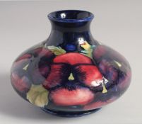 WILLIAM MOORCROFT PANSY PATTERN SQUAT GLOBULAR VASE on a blue ground. W. Moorcroft in blue.