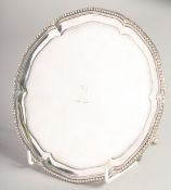 A GEORGE III SILVER CIRCULAR SALVER by HESTER BATEMAN with bead and pie crust edge. 7ins diameter,