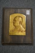 A small bronze portrait bust plaque.