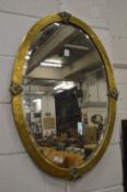 A decorative brass framed oval wall mirror.
