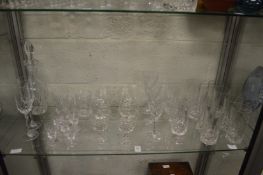 A shelf of glass drinking glasses and a decanter,