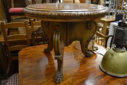 A walnut circular coffee table on three carved feet.