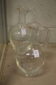 A pair of plain glass bulbous shaped carafes.