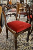 A set of eight Victorian carved rosewood dining chairs with re-upholstered drop-in seats on turned