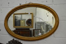 A gilt framed oval mirror.