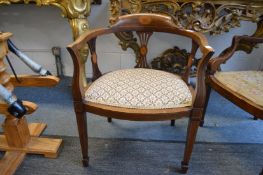 An Edwardian inlaid mahogany horseshoe shaped armchair.