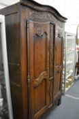 An 18/19th century French oak two door armoire with carved decoration.