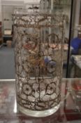 A large cylindrical glass vase overlaid with decorative white metal mount.