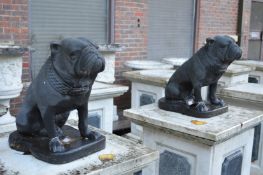 A pair of black painted composite garden ornaments modelled as seated pug dogs.