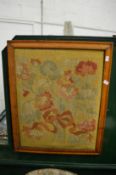 A woolwork tapestry of flowers in a maple frame.