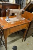 A electric sewing machine housed in a walnut table.