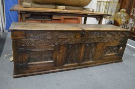 An 18th century oak coffer with plank top, the frieze carved with date 1687 above a pair of carved