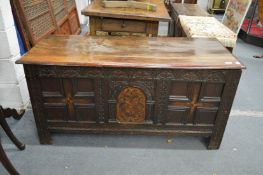 A good 18th century oak coffer with plank top, the front with carved frieze and inlaid panels.