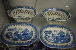 A pair of willow pattern blue and white pierced twin handled baskets on stands.