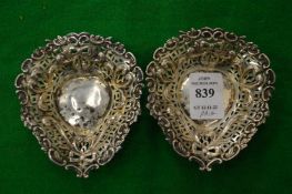 A pair of small silver heart shaped bonbon dishes with pierced decoration.