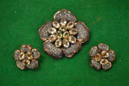 A decorative brooch and a pair of matching ear clips.