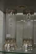 A pair of cylindrical glass vases with decorative white metal mounts.
