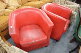 A pair of red leather cloth tub shaped armchairs.