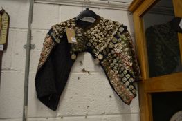 An unusual cape or jacket with metal work and shell work decoration.