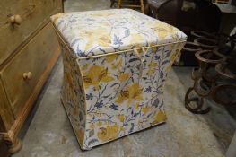 A concave sided upholstered box ottoman.