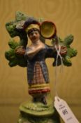 A small Staffordshire figure of a girl by a tree.