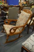 A Victorian mahogany framed rocking chair with arms.