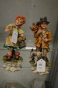 A pair of Capodimonte figures of a boy and girl.