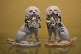 A pair of porcelain models of seated dogs with baskets in their mouths.
