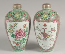 A PAIR OF FAMILLE ROSE PORCELAIN VASES with metal covers, painted with reverse panels of flowers and