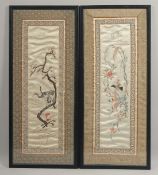 A PAIR OF 20TH CENTURY CHINESE EMBROIDERED SILK PANELS, depicting birds and flora, 63cm x 27cm.
