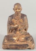 A TIBETAN CARVED STONE SEATED FIGURE, with traces of gold paint, inscribed to the base, 18.5cm