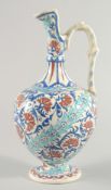 A TURKISH GLAZED POTTERY EWER, painted with blue, turquoise and red floral motifs, 35cm high.