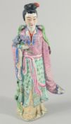 A CHINESE FAMILLE ROSE PORCELAIN FIGURE, of a robed female holding flowers, 31cm high.