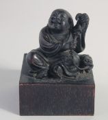 A CHINESE CARVED WOOD IMMORTAL, on a square form base, the base with seal characters, 13cm high.