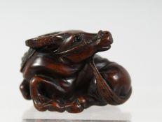 A JAPANESE CARVED WOODEN NETSUKE of a recumbent oxen, signed to base. 4cm wide