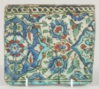 A 18TH/19TH CENTURY IZNIK GLAZED POTTERY TILE, decorated with foliate motifs in blue, turquoise