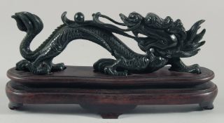 A CHINESE DARK GREEN HARDSTONE CARVING OF A DRAGON, on a fitted hardwood base, 27cm long on stand.