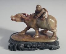 A CHINESE CARVED SOAPSTONE FIGURE of a boy riding an oxen, the carving with carved fitted hardwood