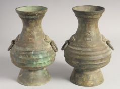 A PAIR OF BRONZE TWIN HANDLE VASES, each with characters and two bat formed drop-ring handles,