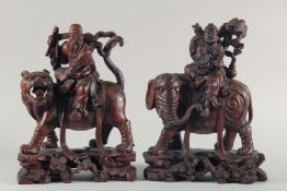 A PAIR OF CHINESE CARVED HARDWOOD FIGURES, each of an immortal atop an elephant and a tiger on a