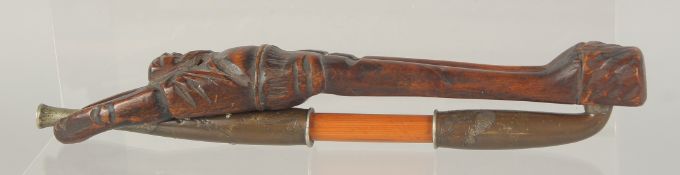 A JAPANESE METAL MOUNTED WOODEN TOBACCO PIPE with figural carved wood holder, pipe 20cm long.