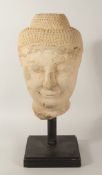 A LARGE CARVED STONE BUDDHA HEAD, raised on a hardwood stand, head 40cm high.