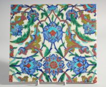 AN IZNIK STYLE GLAZED POTTERY TILE, painted with foliate motifs, 24cm x 26.5cm.