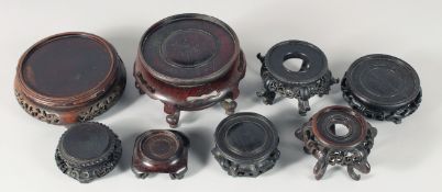 A COLLECTION OF EIGHT CHINESE CARVED HARDWOOD STANDS, largest 15cm diameter overall, (8).